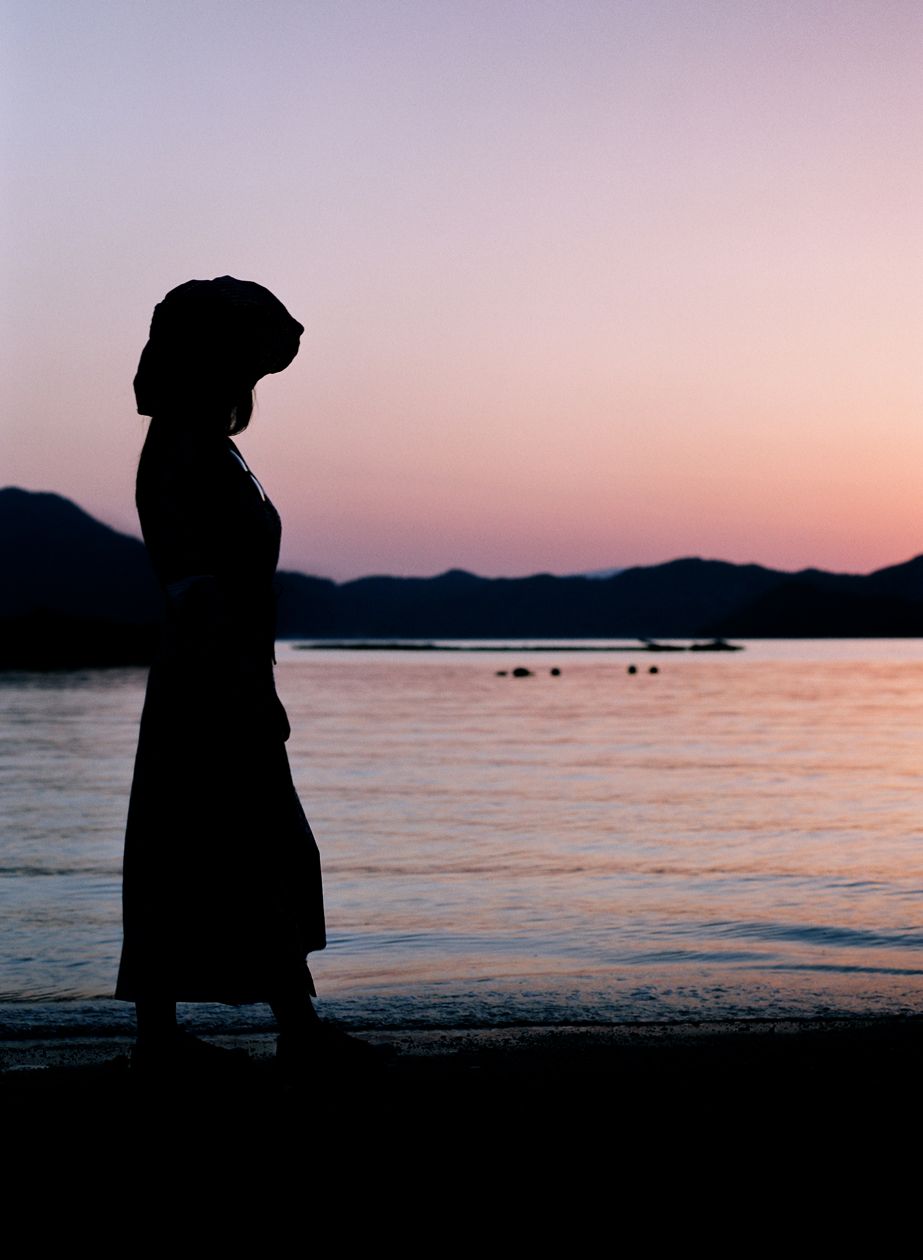 silhouette of woman standing on beach during sunset